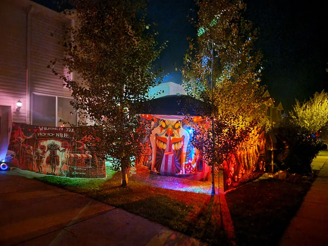 The Haunted Carnival at night: a tent front painted as a giant clown's mouth, lit in red and blue, beside a Welcome to the Horror Nights Carnival banner.